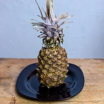 Pineapple on the kitchen table in a plate Stock Photos