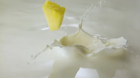 Pineapple pieces falling in milk and splashing Stock Footage 149434240