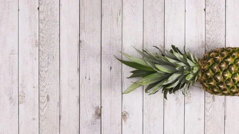 Pineapple rolling in place on right side of  wooden theme. Stop motion Видео 141170016