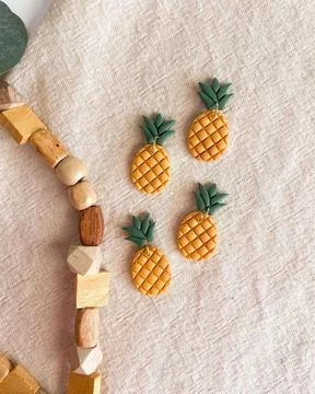 Pineapple shape yellow color earring on bed sheet. Modern jewelry earring f.. Stock Photos
