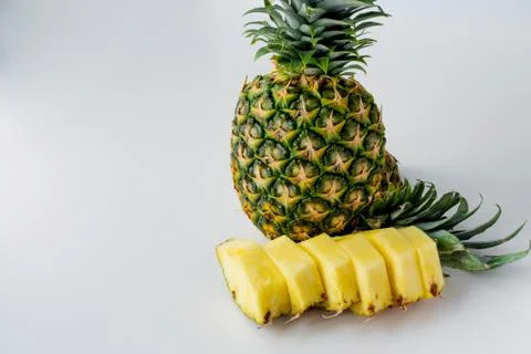 Pineapple stands on a light gray uniform surface. Stock Photos