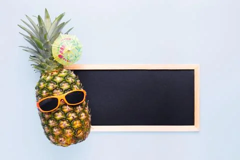 Pineapple in sunglasses with empty blackboard for your text on blue background Stock-Fotos