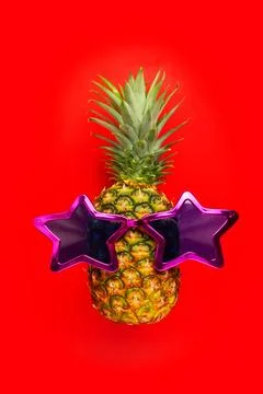 Pineapple with sunglasses on red background. Pineapple in star glasses. Stock Photos
