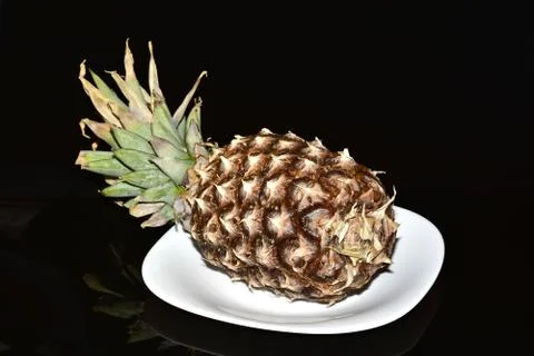 Pineapple on a white dish on a black background Foto stock