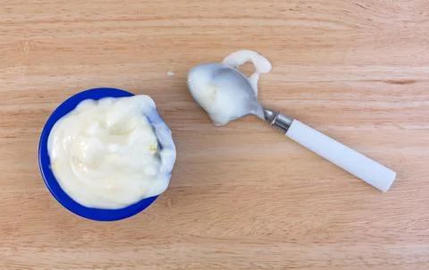 Pineapple yogurt on a wood table with spoon and spill Stock Photos