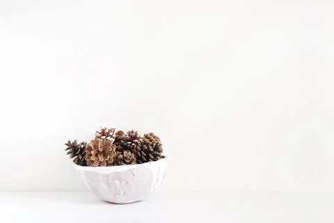Pinecones in ceramic bowl on white table. Christmas styled stock photo, holiday Fotos Stock
