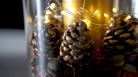 Pinecones in a glass container with a candle and lights, christmas decorations Video stock 120943284