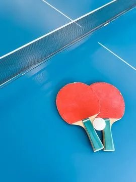 Ping Pong Table with Rackets and Ball on Blue Surface Stock Photos