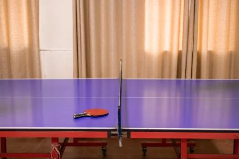 A ping pong table. A red table tennis bat is placed on the ping pong tables i Stock Photos