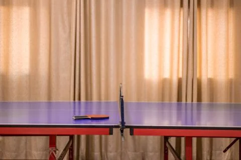 A ping pong table. A red table tennis bat is placed on the ping pong tables i Stock Photos