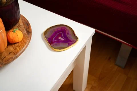Pink agate coaster on the side of white coffee table Stock Photos
