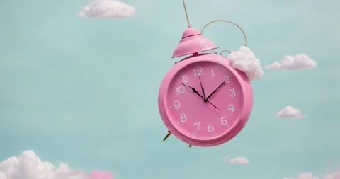 Pink alarm clock closeup with clouds. Pink clock swings like a pendulum  Stock Footage 263239661