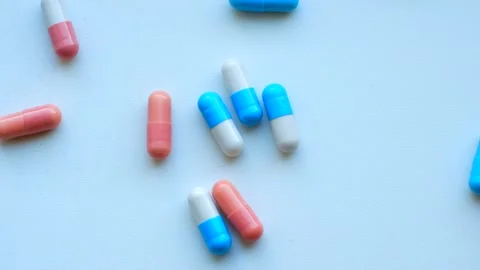 Pink and blue capsules falling on white background Stock Footage 311942977