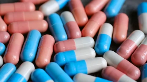 Pink and blue capsules rotating on a grey background Stock Footage 311941828