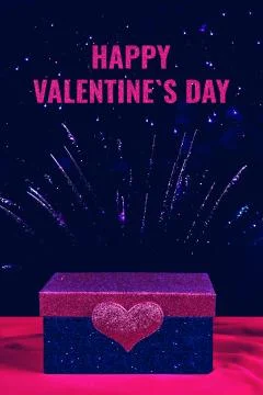 Pink and blue gift box with a glittering heart on it and fireworks on the Stock Photos