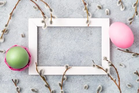 Pink and green easter eggs on gray table with willow twigs and white wooden f Stock Photos