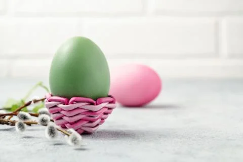 Pink and green Easter eggs in a wicker stand and on a gray table with pussy-w Stock Photos