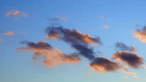 Pink and orange clouds float in a blue sky during sunset. evening sky, sunset Stock Footage 340272241