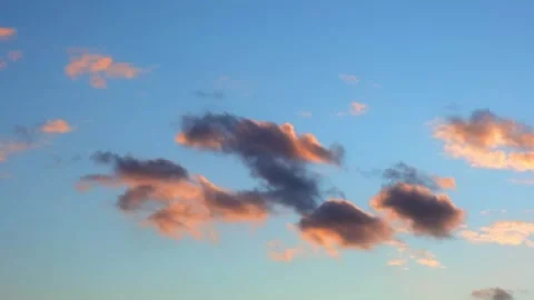 Pink and orange clouds float in a blue sky during sunset. evening sky, sunset Stock Footage 344660834