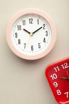 Pink and red wall clock on grey background. Vertical photo Stock Photos
