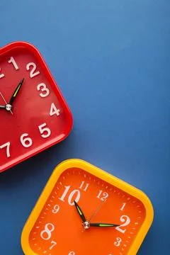 Pink and red wall clock on dark blue background. Vertical photo Stock Photos