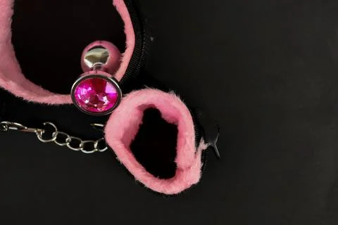 Pink and silver accessory placed on a black surface with a round jewel and chain Stock-Fotos