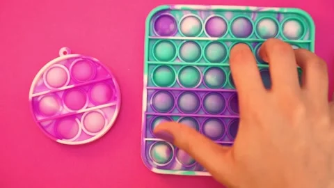 Pink and turquoise green pop it fidget toy for kids, female girl teen hands Stock Footage 155802289