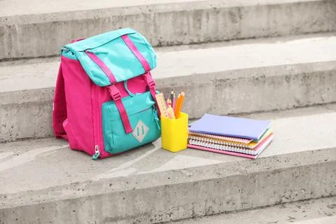 Pink and turquoise school backpack with notebooks and pencils on concrete ste Stock Photos