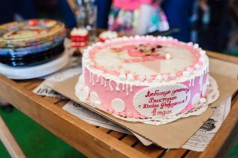 Pink and white custom first birthday cake on a wooden table during an outdoor Stock Photos
