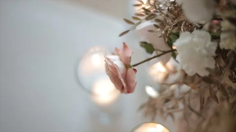Pink-and-white flower hangs over glasses with candles, a top view in a dipped Stock Footage 123267394