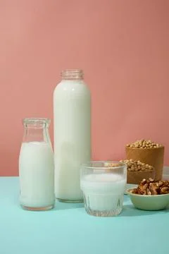 Pink background featured two unbranded bottles and a mug filled with milk. Fe Stock Photos