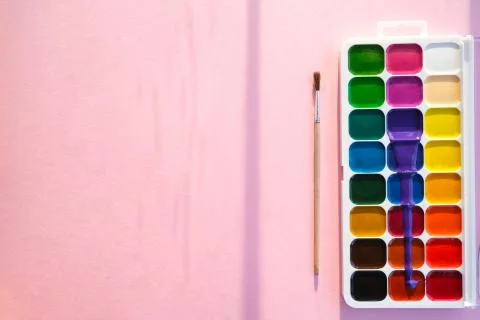 On a pink background, a palette with different terns and a brush. Stock Photos