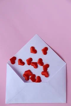 Pink background shows an envelope with red heart shapes spilling out during a Stock Photos