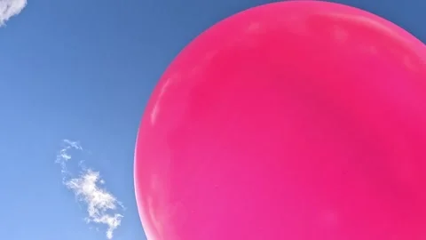 Pink balloon floating gently across clear blue sky Stock Footage 316543114