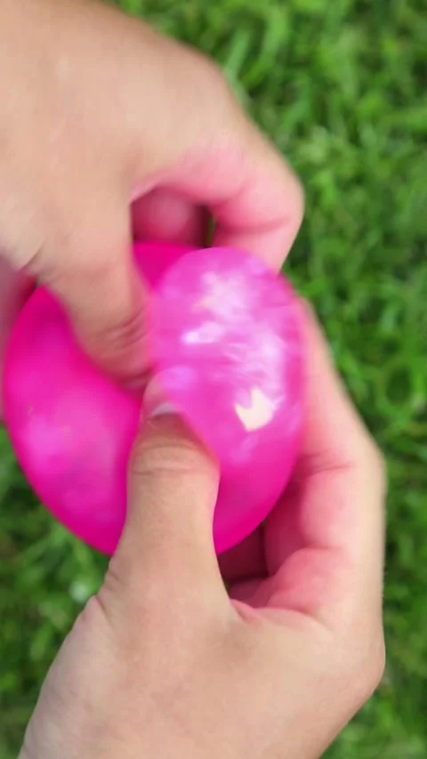 Pink balloon stretched and pressed by hands outdoors Stock Footage 321767692