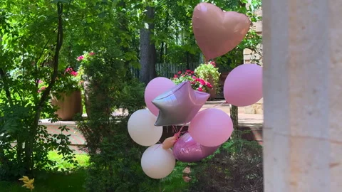 Pink balloons fluttering in the wind in a spring garden Vídeo Stock 310430386