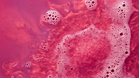 Pink bath bomb ball dissolves in water with white foam bubbles and sparkles Stock-Footage 147385940