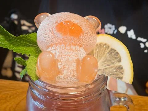 Pink bear-shaped ice cube in a glass jar with lemon and mint Stock Photos