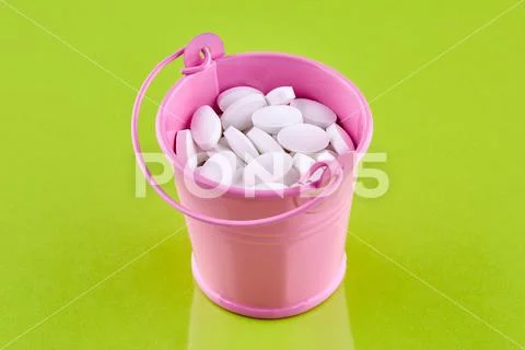 Pink bucket with white pills on green background Stock Photos