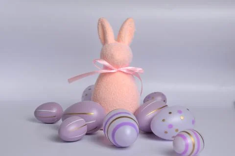 Pink bunny surrounded by Easter eggs on a purple background. Happy Easter. Stock Photos