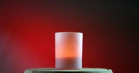 Pink burning candle on red gradient background rotates on the wooden platform Video stock 91629342