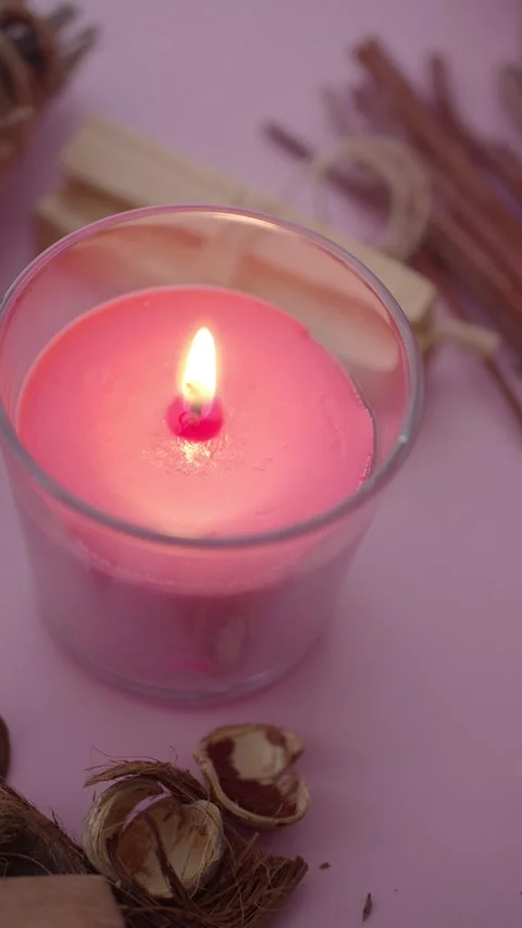 A pink candle burns bright while natural decor surrounds it Stock Footage 327632984