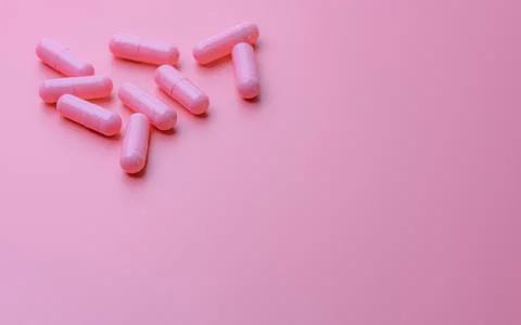 Pink capsule pills on pink background. Woman health insurance budget. Pharmac 库存照片