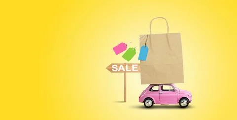 Pink car with shopping paper bag on the roof. Sale concept Stock Photos