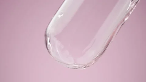 Pink clear liquid pours into a laboratory glass tube, forming bubbles inside Stock Footage 178403693