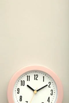 Pink clock on grey background. Top view. Vertical photo Stock Photos