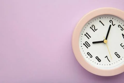 Pink clock on purple background. Top view. Stock Photos