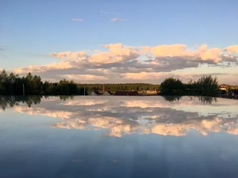 Pink clouds at dawn are reflected in the mirror surface of the glass table. Stock Photos