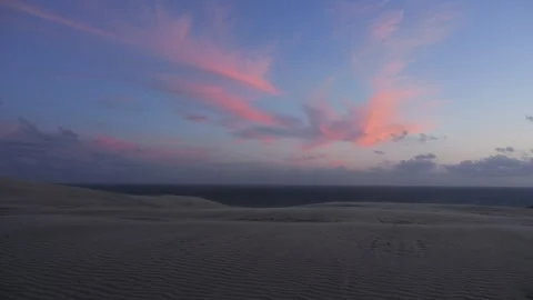 Pink clouds moving over sand dunes at dusk Stock Footage 338092846