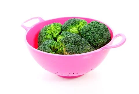 Pink colander with broccoli vegetable Foto stock